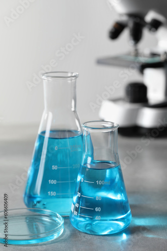Different laboratory glassware with light blue liquid on table