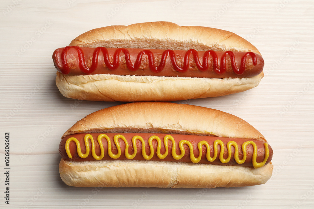 Fresh delicious hot dogs with sauces on white wooden table, top view Fresh delicious hot dogs with sauces on white wooden table, top view