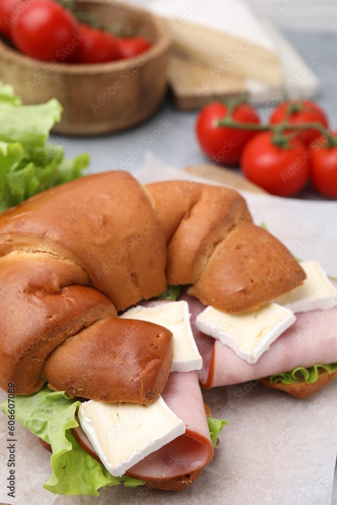Tasty crescent roll with brie, ham and lettuce on grey table, closeup Tasty crescent roll with brie, ham and lettuce on grey table, closeup