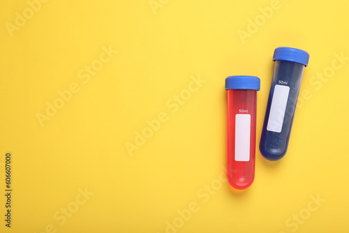 Test tubes with colorful liquids on yellow background, flat lay and space for text. Kids chemical experiment set
