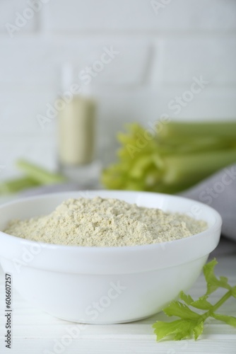 Natural celery powder in bowl and fresh stalks on white table, closeup