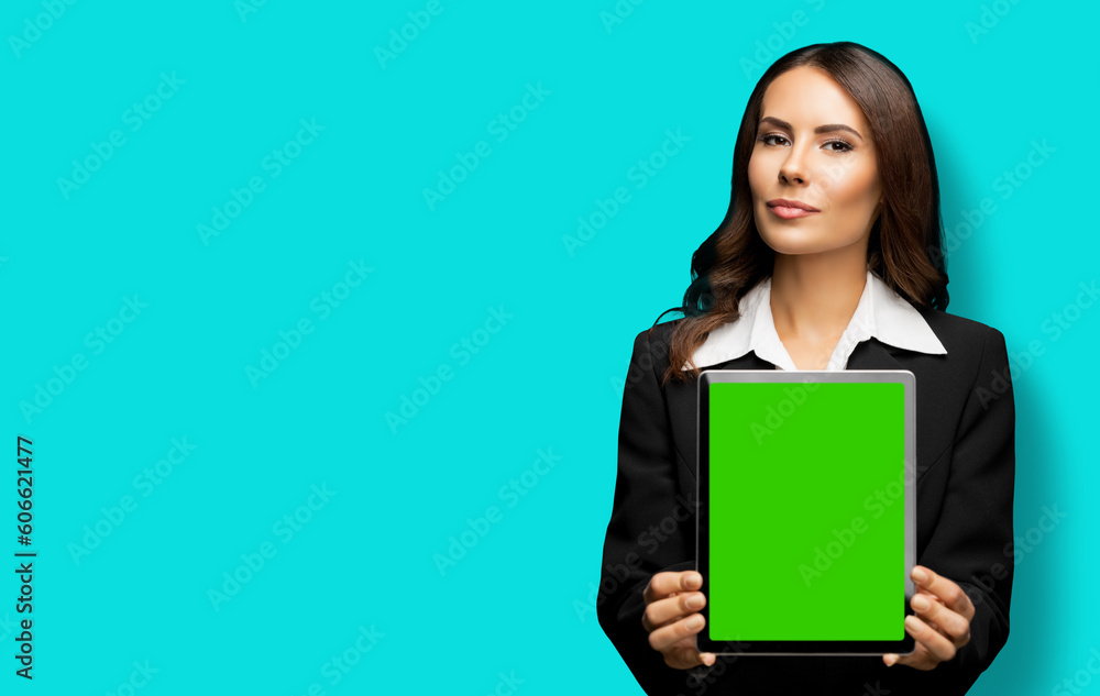 Portrait of young brunette businesswoman showing tablet pc, touchpad, with green chroma key screen, on aqua marine background. Confident attractive business woman at office. Portrait of young brunette businesswoman showing tablet pc, touchpad, with green chroma key screen, on aqua marine background. Confident attractive business woman at office.