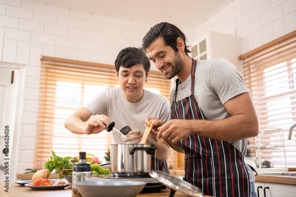 Two guys of different ethnicity having fun while making spagghetti together on kitchen. Concept of gay LGBTQ couples and everyday life at home . Asian and hispanic man cooking healthy food. Two guys of different ethnicity having fun while making spagghetti together on kitchen. Concept of gay LGBTQ couples and everyday life at home . Asian and hispanic man cooking healthy food.