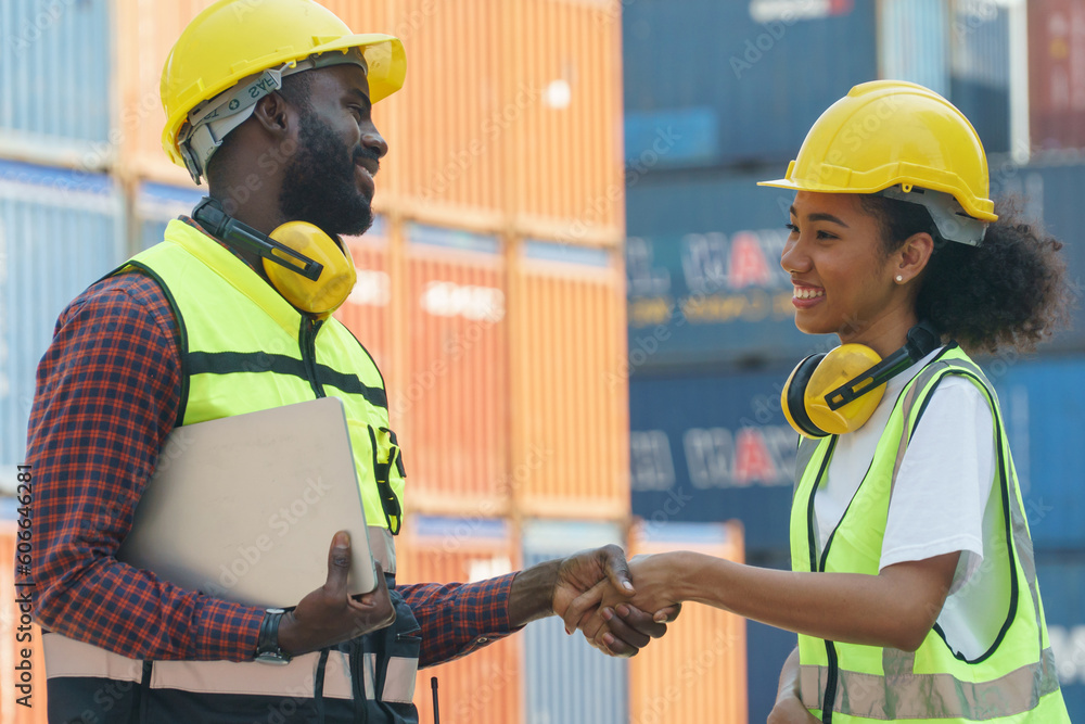 group of two african american engineer holding laptop computer talking with colleague and checking list inventory loading Containers box at warehouse logistic in Cargo . couple worker shaking hand group of two african american engineer holding laptop computer talking with colleague and checking list inventory loading Containers box at warehouse logistic in Cargo . couple worker shaking hand