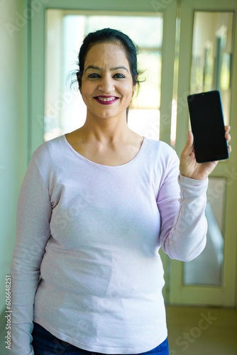 Happy indian woman showing smartphone screen with thumps up.