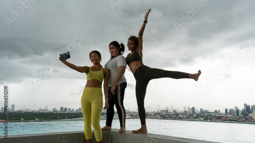 Friends having fun at swimming pool on skycraper roof top Selfie photo after finish yoga meditates against modern skyscrapers with swimming pool. Young girl spending time outside roof top