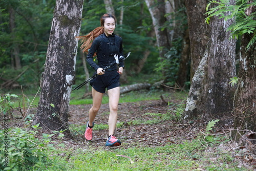 Healthy young woman running on mountain trail at morning tropical forest trail