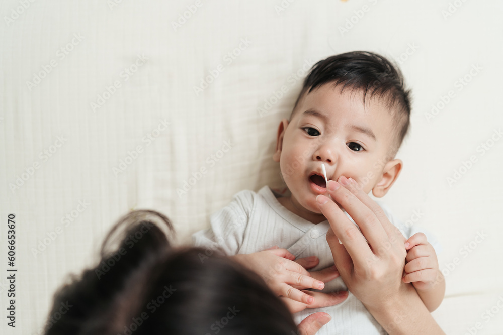 Top view, Asian baby nose care with cotton bud. Mother take care nostril cleaning of little baby. Baby care concept. Top view, Asian baby nose care with cotton bud. Mother take care nostril cleaning of little baby. Baby care concept.