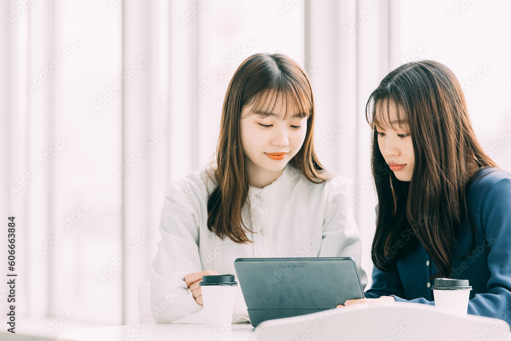 タブレットを見ながら話す2人の日本人ビジネスウーマン タブレットを見ながら話す2人の日本人ビジネスウーマン