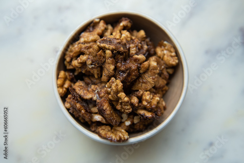 Brown candied caramelized walnuts in round plate, top view