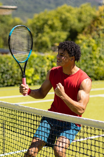 Cheerful biracial young man holding tennis racket pumping fist after winning game © wavebreak3