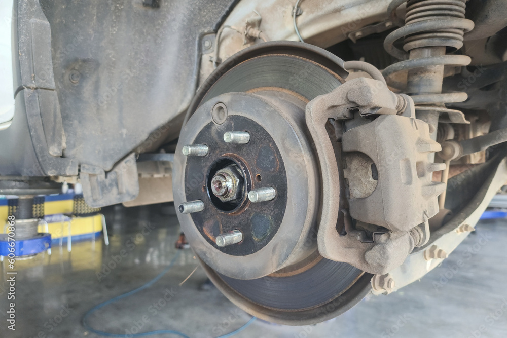 Fototapeta premium Close-up at car disc brake system during maintenance at the garage. Vehicle equipment object photo, selective focus.