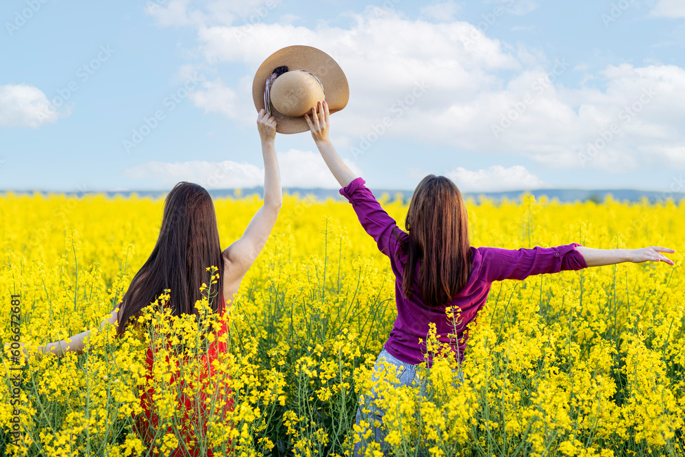 Φωτογραφία Two beautiful young long hair woman in the middle of rapeseed yellow field with