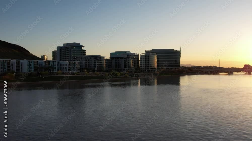 Aerial drone pan shot of a building complex beside Tempe Town Lake reservoir in Arizona, United States during evening time. Aerial drone pan shot of a building complex beside Tempe Town Lake reservoir in Arizona, United States during evening time.