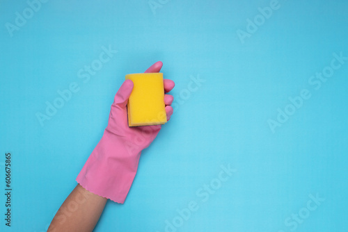 woman wearing pink cleaning gloves on light blue background holding cleaning sponge