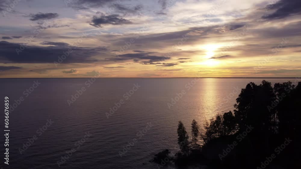 Silhouettes of trees against the background of the sea and the setting sun. Aerial photography of water. Silhouettes of trees against the background of the sea and the setting sun. Aerial photography of water.