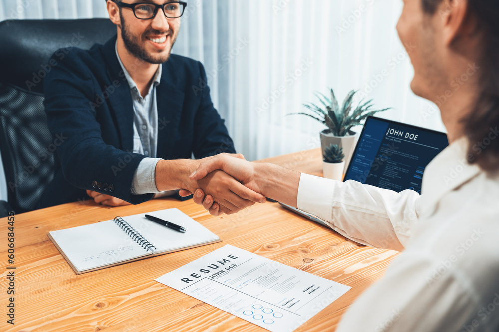 After successful meeting or job interview, two happy businessmen shake  hands over resume papers. HR manager extend hand for congratulatory  handshake to job applicant, welcoming new employee. Entity Stock Photo