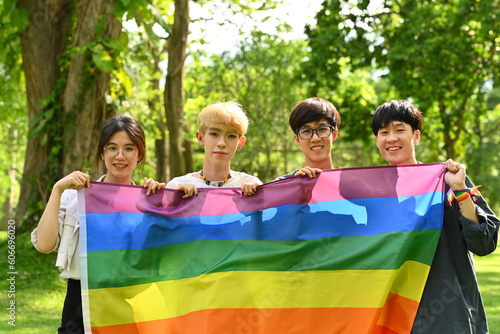 Group of young activist holding pride rainbow flag, supporting LGBTQ community and shooting of equality social