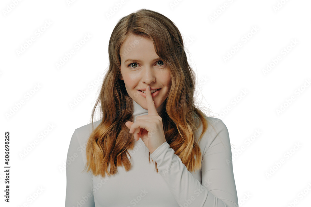 Smiling young millennial woman holding index finger on her lips over blue studio wall background Smiling young millennial woman holding index finger on her lips over blue studio wall background