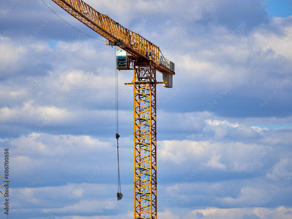 Construction cranes on a construction site against the blue sky