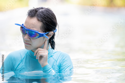 Stressed asian girl had tinnitus,problem with water entering the ear canal while swimming,female people cleaning ears after diving in swimming pool,otitis externa,swimmer's ear,health care concept photo