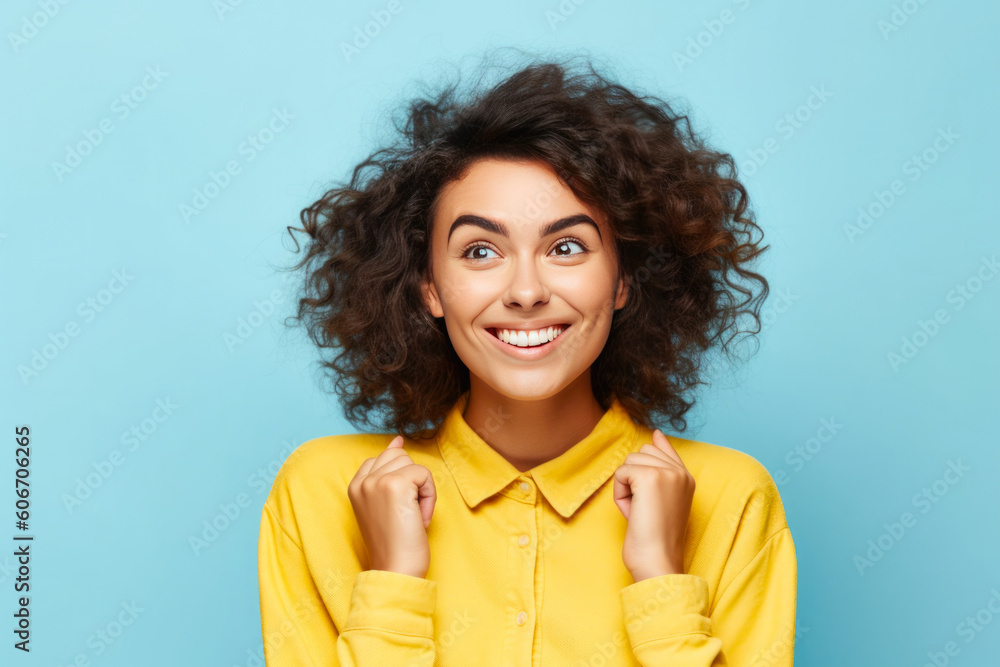 Excited young woman in happiness state, dressed with a yellow shirt. Isolated on a clean blue background. Excited young woman in happiness state, dressed with a yellow shirt. Isolated on a clean blue background.