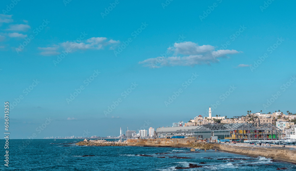 Tel Aviv-Yafo, Israel, April 12, 2022. panorama of the waterfront of the old city of Jaffa and the construction of a new shopping center against the blue sky with clouds, the ancient port, and the