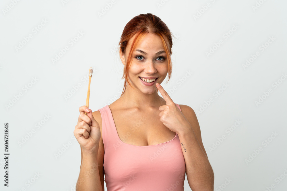 Teenager Russian girl isolated on white background with a toothbrush and happy expression Teenager Russian girl isolated on white background with a toothbrush and happy expression