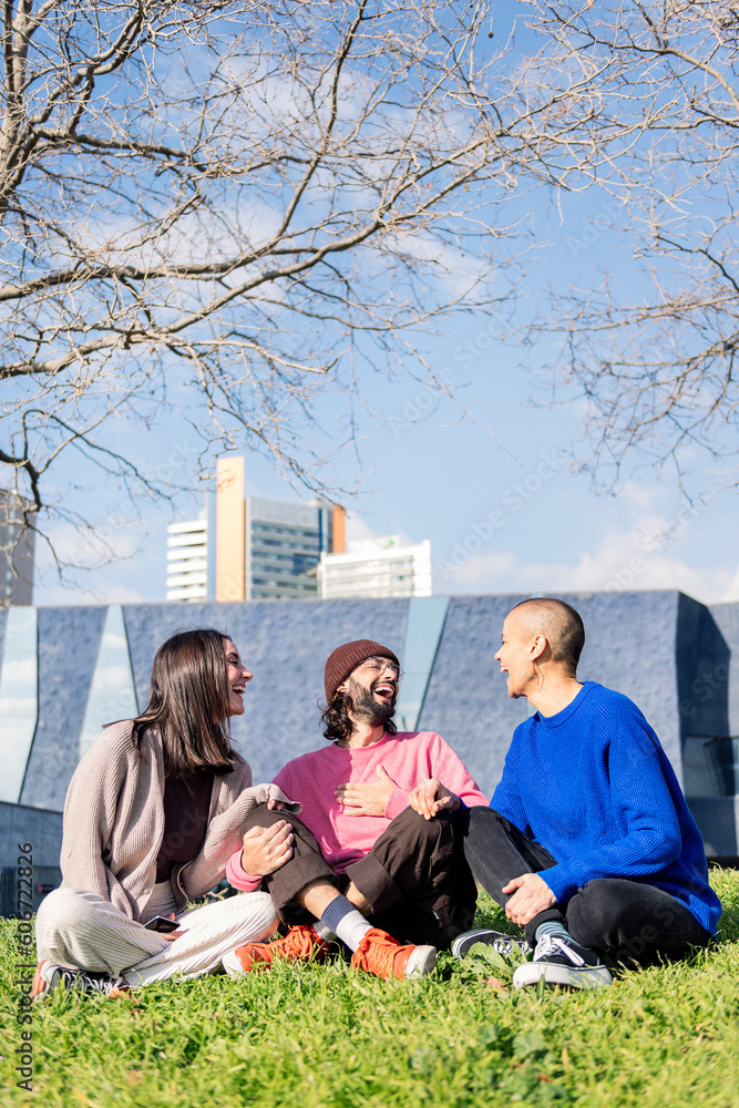 Φωτογραφία three young friends laughing happy sitting in the lawn at the city park in a sun