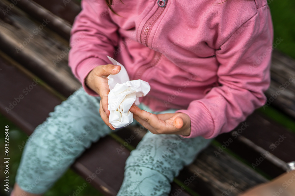 One toddler girl wipes his hands with a tissue, close up, healthy hygiene early child development concept