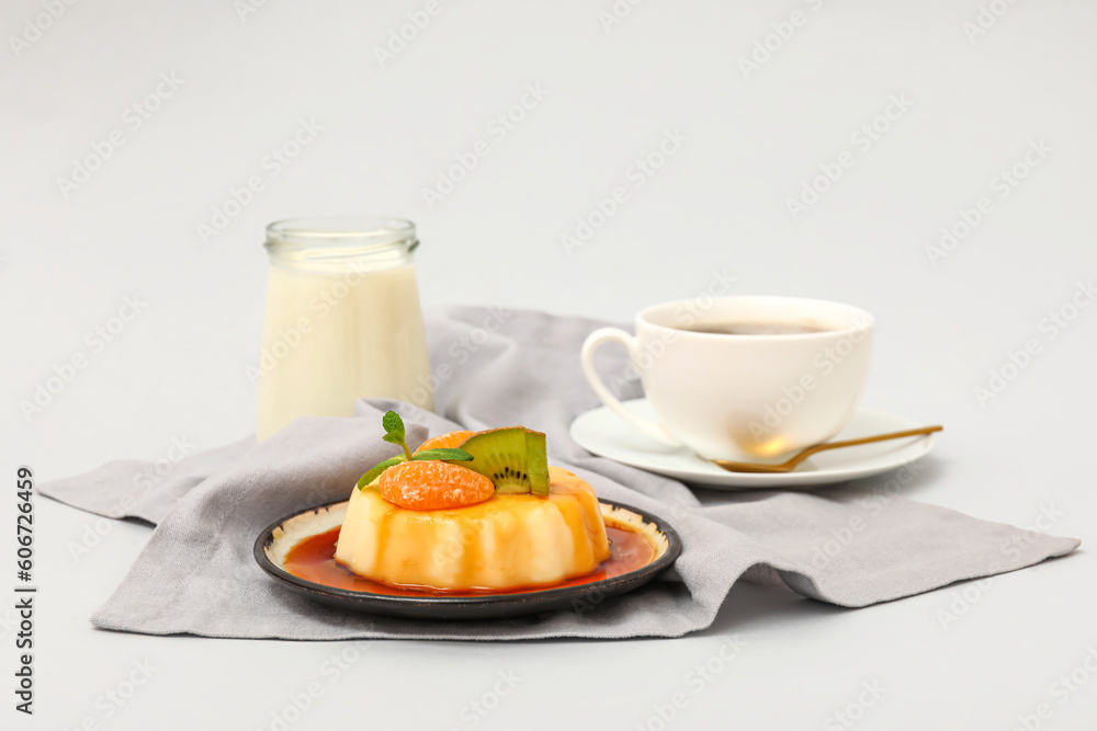 Plate with delicious pudding, kiwi and tangerines covered by caramel syrup on grey background Plate with delicious pudding, kiwi and tangerines covered by caramel syrup on grey background