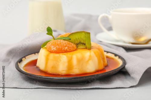 Plate with delicious pudding  kiwi and tangerines covered by caramel syrup on grey background