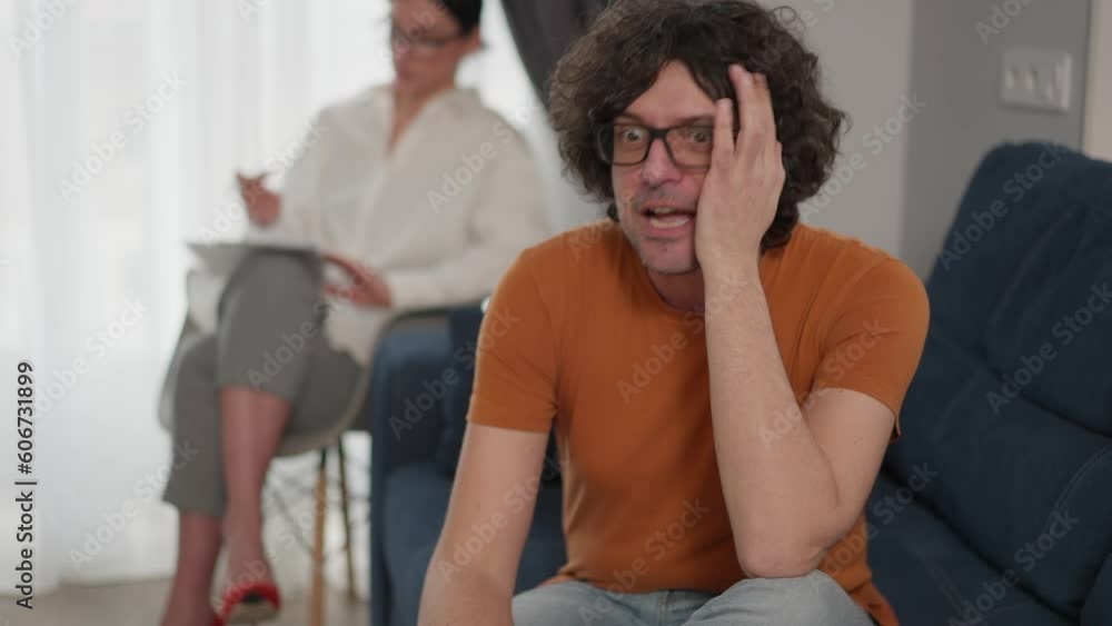 Upset caucasian man lying on sofa and telling about problems while female psychologist helping him to calm down during counseling session Upset caucasian man lying on sofa and telling about problems while female psychologist helping him to calm down during counseling session