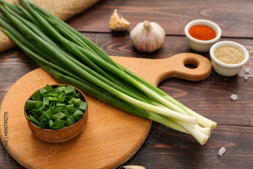 Board with fresh green onion on wooden background