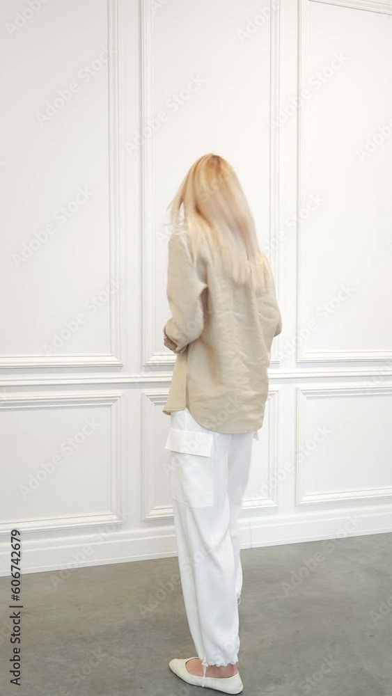 Cute woman in loose cotton shirt, white breeches and flats posing in white room Cute woman in loose cotton shirt, white breeches and flats posing in white room