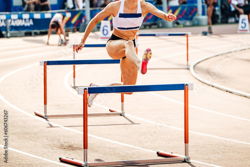 female athlete running 400 meters hurdles race in summer athletics championships
