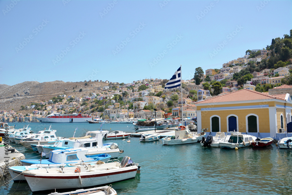 A waterfront with a lot of fishing boats and town with hills on background   