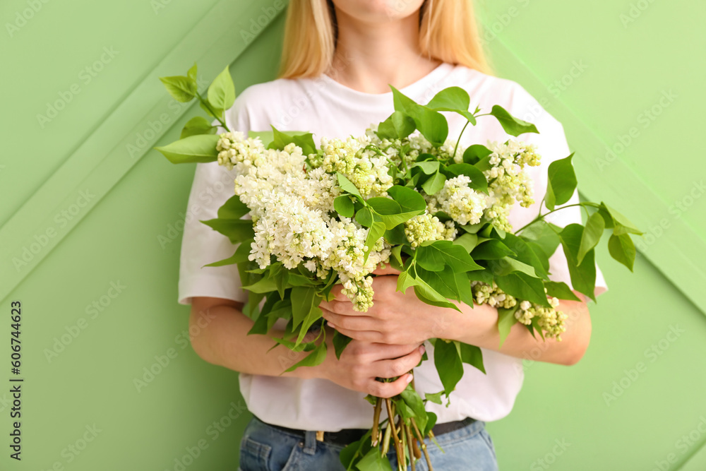 Woman holding bouquet of white lilacs near green wall