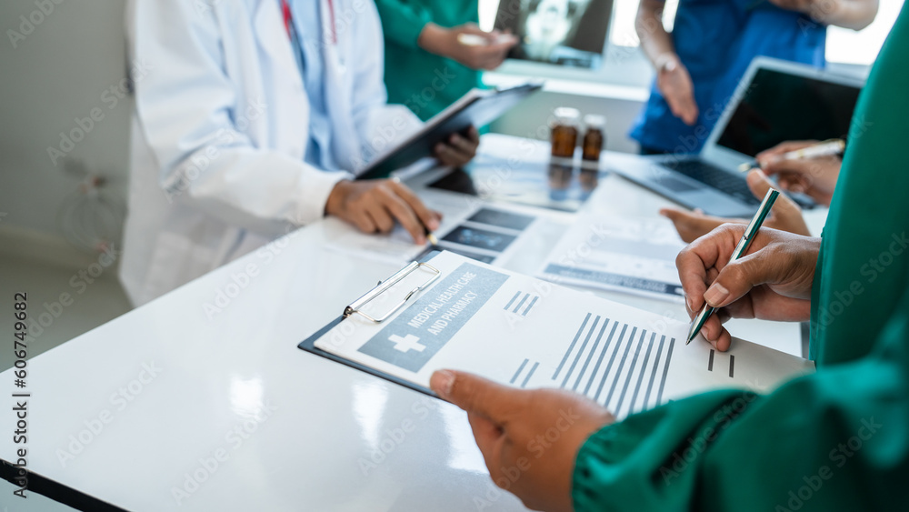 Medical surgical team meeting with doctors in white lab coats and surgical gowns sitting at table discussing x-ray of patient history. success of medical health care. Medical surgical team meeting with doctors in white lab coats and surgical gowns sitting at table discussing x-ray of patient history. success of medical health care.