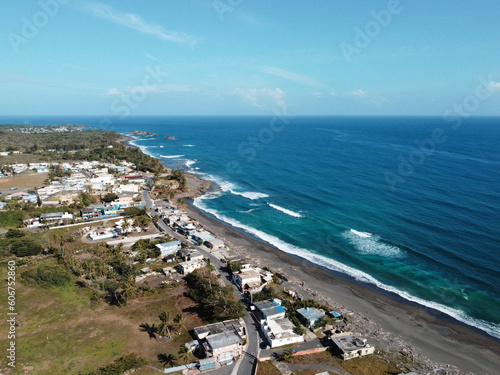 Aerial view of white foamy waves crashing on a sandy beach on a sunny day