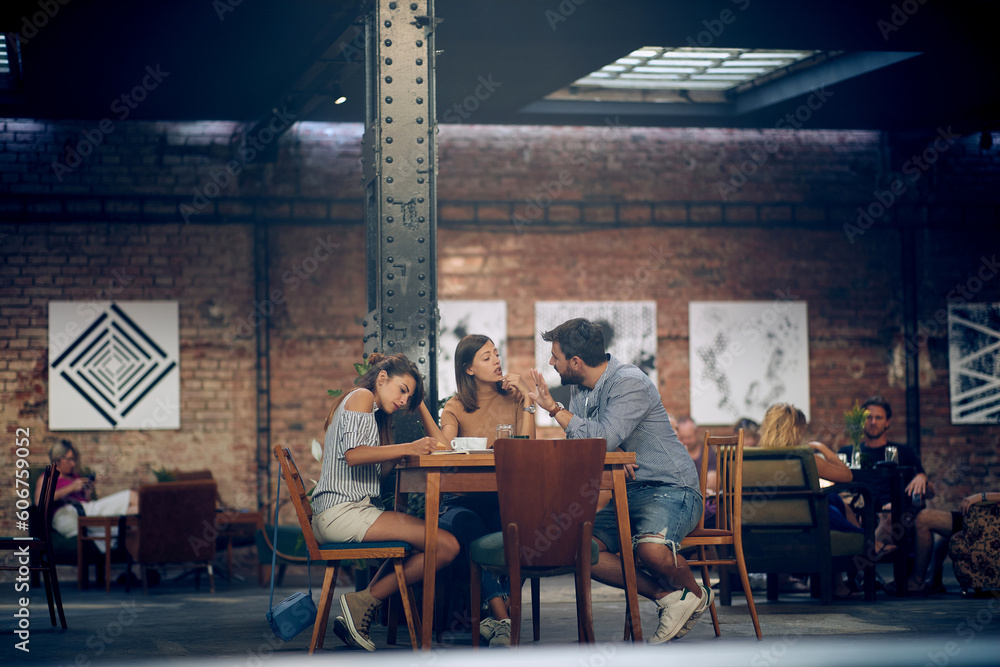 Young friends talking and having coffee together in a modern cafeteria. Young friends talking and having coffee together in a modern cafeteria.