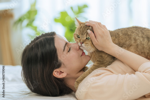 Young Asian Woman Kissing Cat in Bedroom Morning