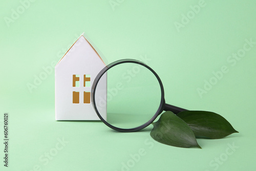 Concept of green tax credit - little house with magnifying glass near it and green leafs.