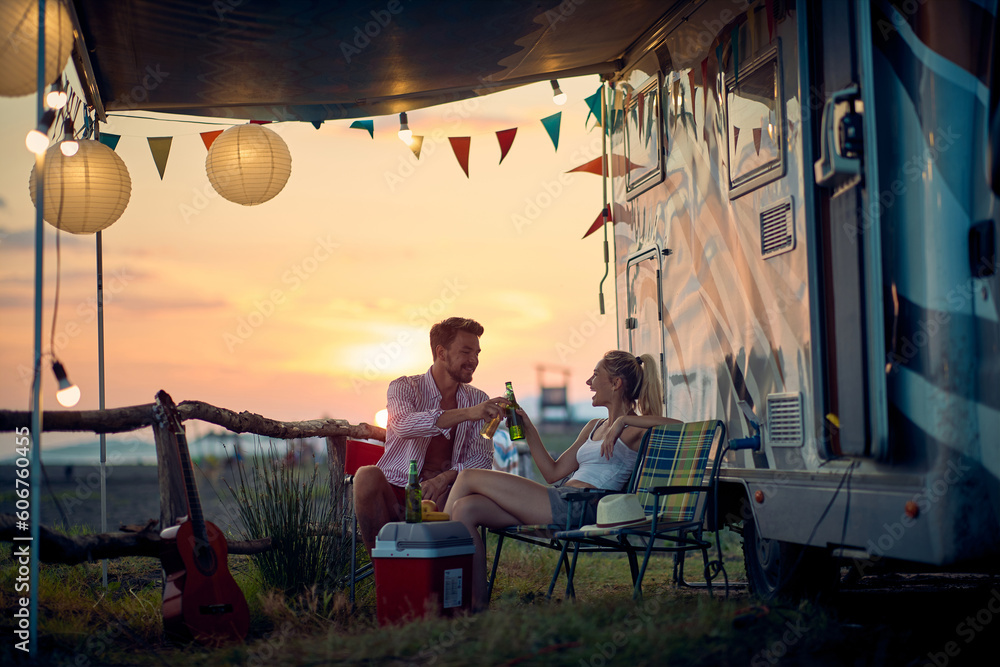 A young couple is sitting in the camp during vacation and drinking. Vacation, relationship, camping, nature