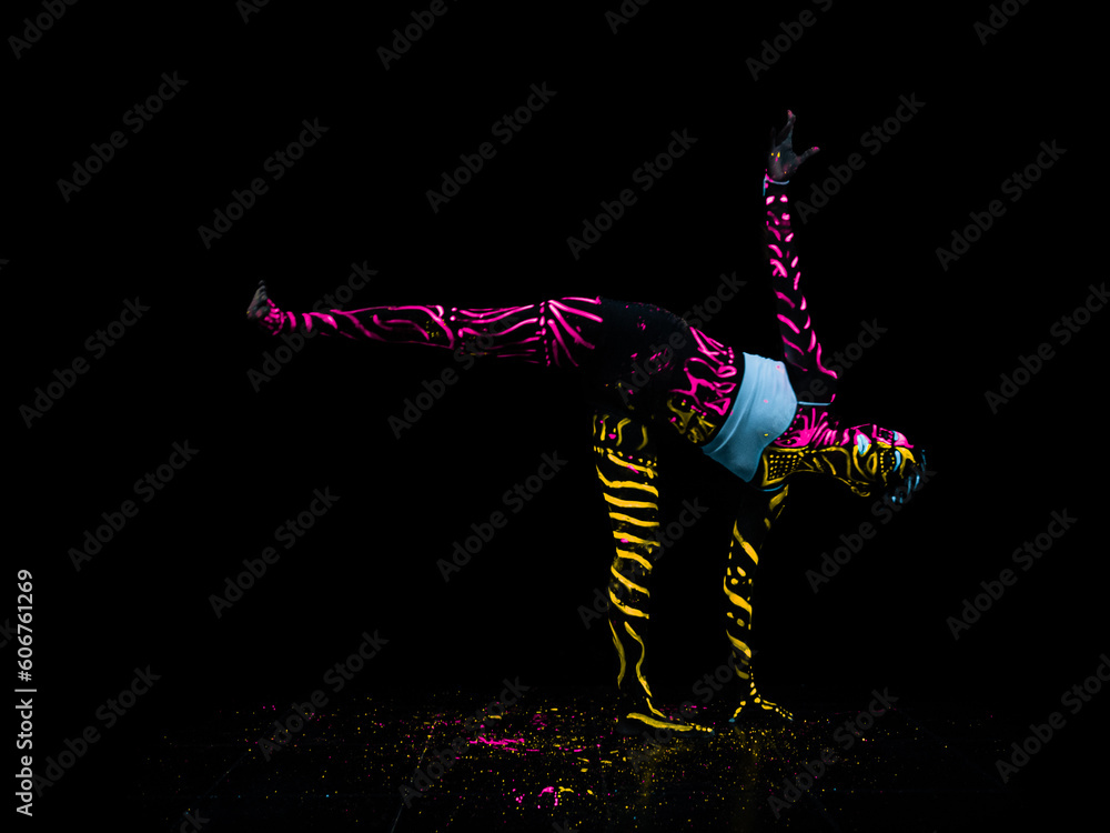 Fototapeta premium Girl is doing yoga in black light, neon, fluorescent, body painting