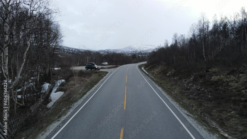 Drone view over the road by a frozen lake surrounded by snow-covered mountains Drone view over the road by a frozen lake surrounded by snow-covered mountains