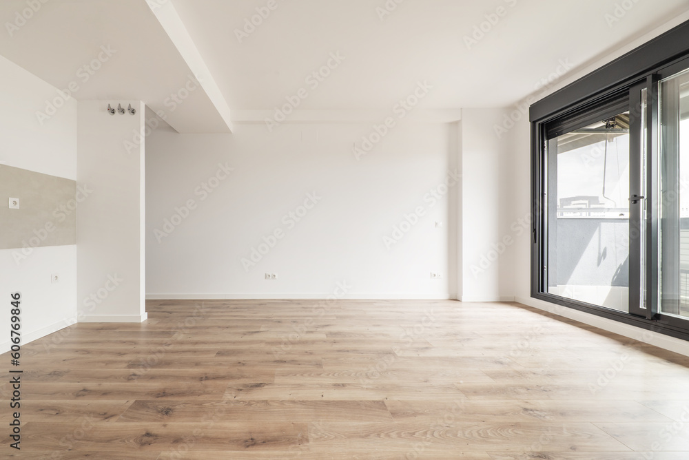Living room of an empty apartment with light wooden floors and access to a terrace Living room of an empty apartment with light wooden floors and access to a terrace