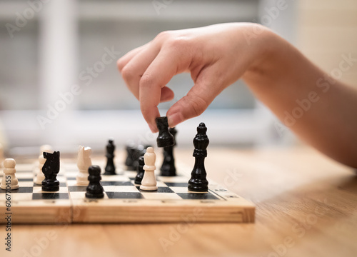 Hand of obscured girl holding chessman playing chess