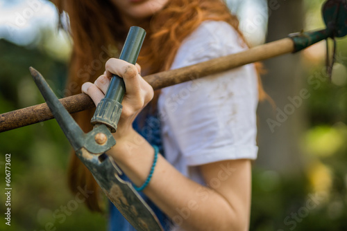 Female ginger gardener holding shovel and digger in her hands. Close up shot
