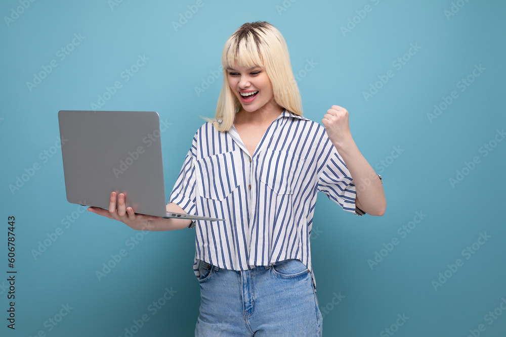 joyful cute blond 25 year old female person in a striped blouse and jeans with a laptop joyful cute blond 25 year old female person in a striped blouse and jeans with a laptop